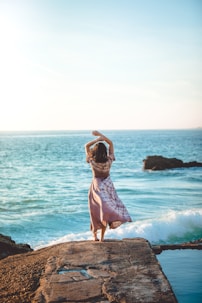 woman standing on cliff raiser her hands