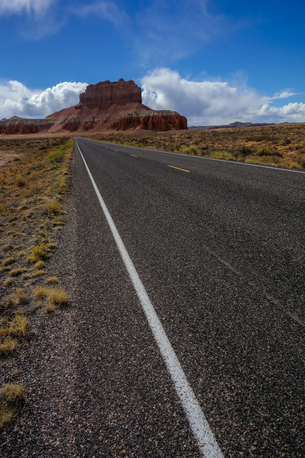 Carretera de asfalto gris cerca de Brown Mountain bajo cielo azul durante el día