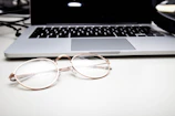Close-up of eyeglasses on a desk with software open in the background