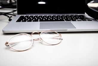 A sleek black and gold-themed workspace with eyewear samples and marketing analytics on a laptop screen.