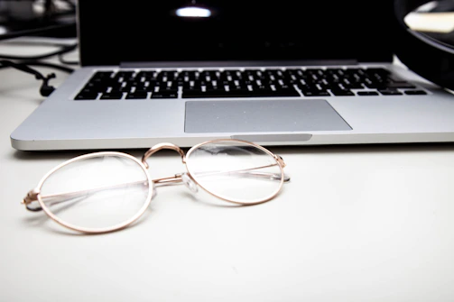 Close-up of eyeglasses on a desk with software open in the background