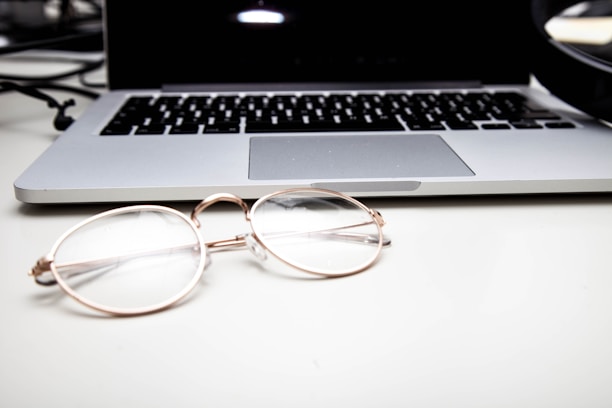 A sleek black and gold-themed workspace with eyewear samples and marketing analytics on a laptop screen.