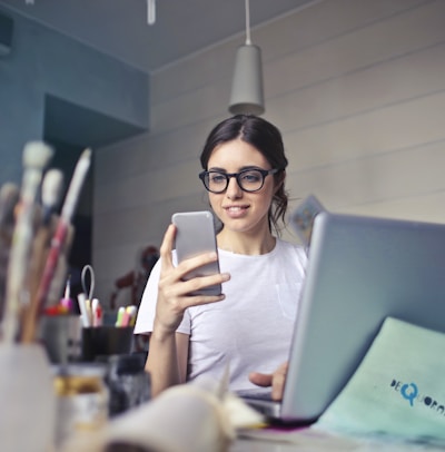 woman in white shirt using smartphone