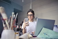 Woman at a desk looking at an iPhone