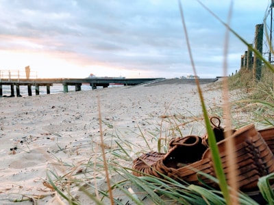 Pair of espadrilhas resting against a natural woven basket on a beach