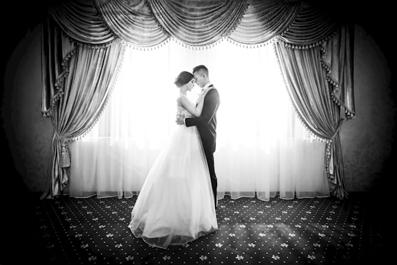 A warm, candid shot of a bride and groom sharing a quiet moment, softly lit in classic black and white.