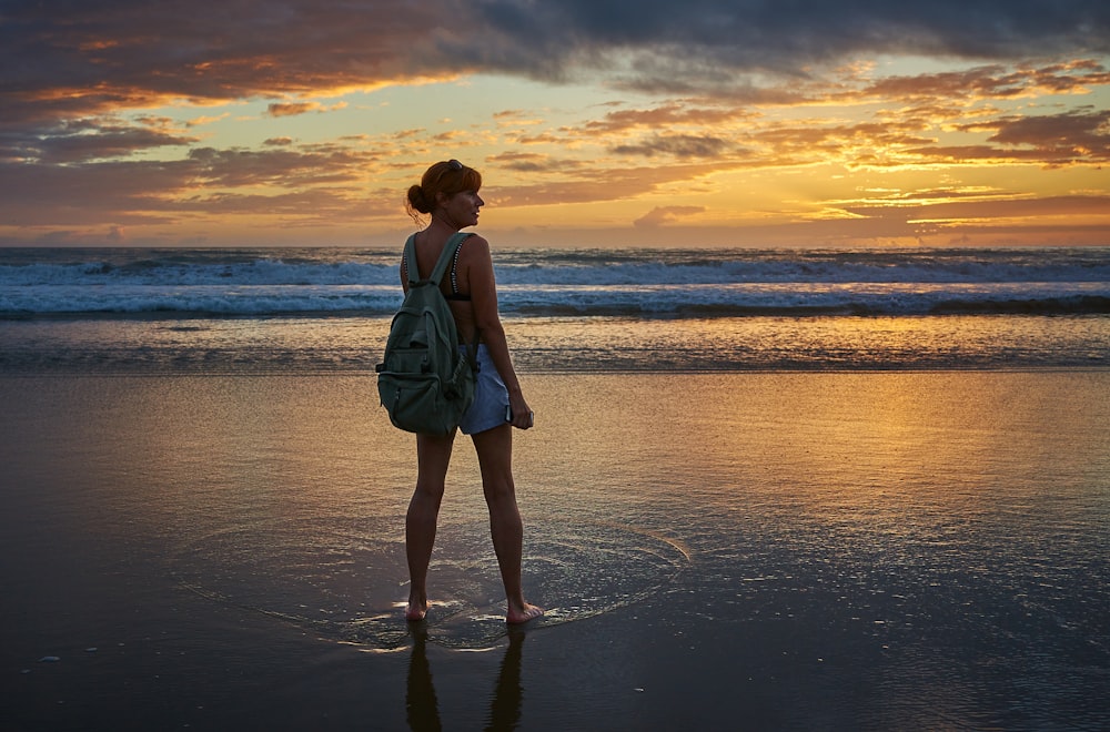 Donna in piedi vicino alla riva del mare durante l'ora d'oro