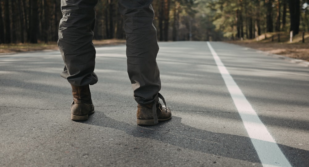 person standing in middle of concrete road near trees