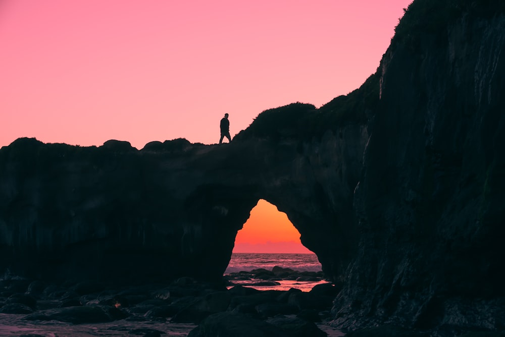 silhouette d’homme marchant sur le sommet d’un gros rocher
