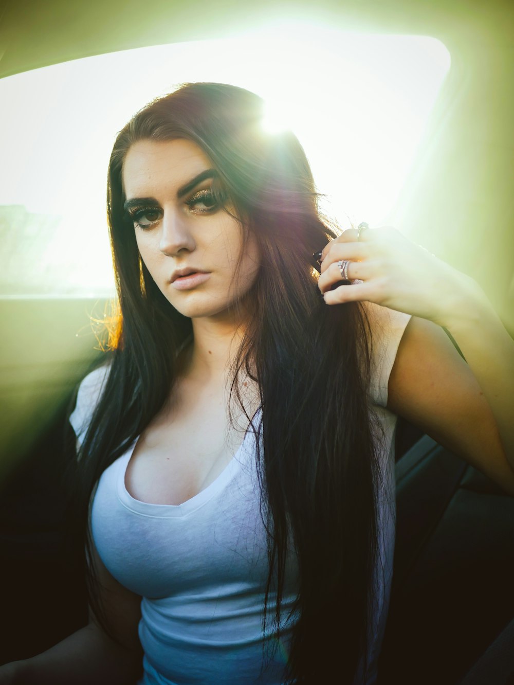 woman wearing white scoop-neck shirt holding her hair inside car