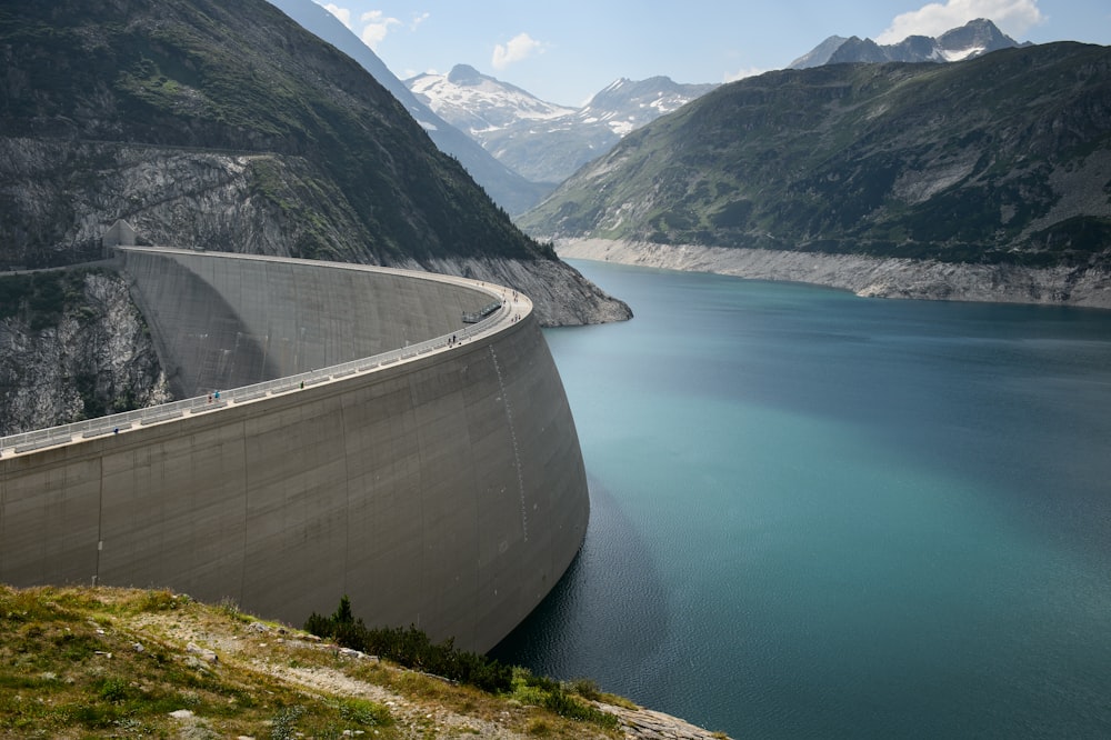 Foto eines Betondamms in einem See in der Nähe von Bergen während des Tages