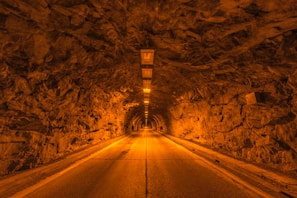 A tunnel entrance carved into a rocky hillside, illuminated by soft lighting.