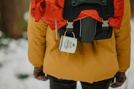 selective focus photograph of person wearing orange coat and black backpack
