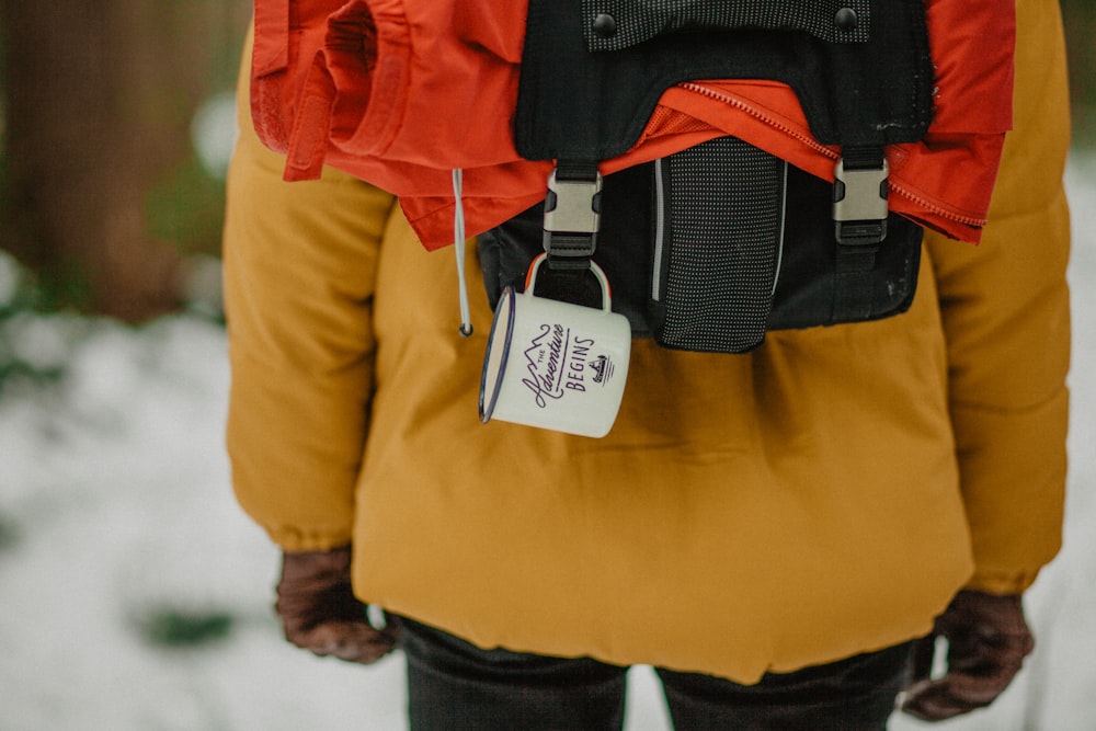 selective focus photograph of person wearing orange coat and black backpack