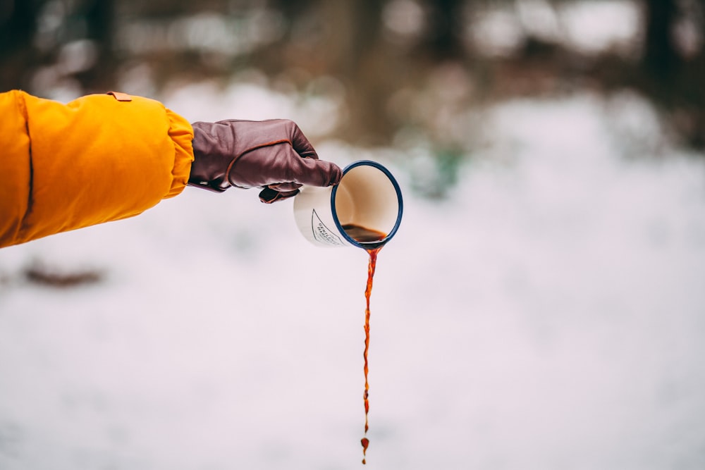 person pouring out coffee from white ceramic cup