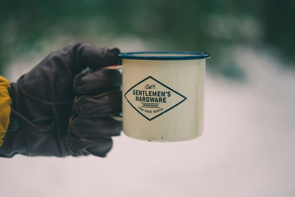 persona sosteniendo una taza de cerámica blanca