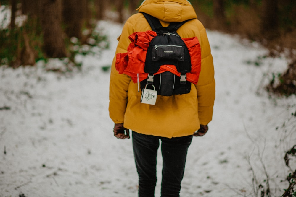 person carrying black backpack in road