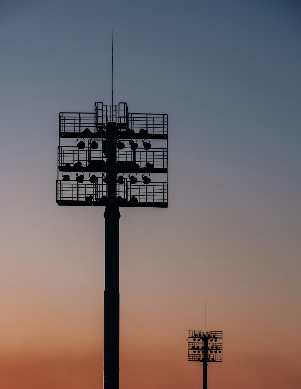 silhouette of two spot light tower