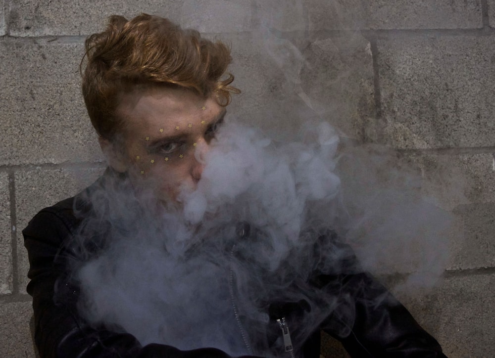 Mann sitzt umgeben von Rauch