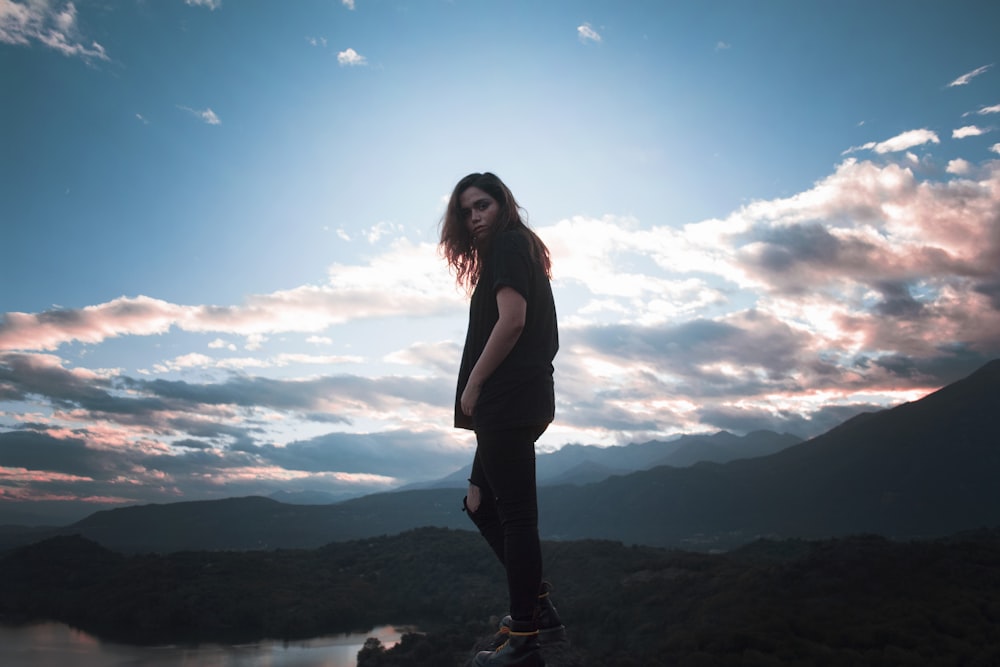 woman putting her hand in pocket standing near mountain