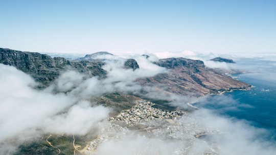 photo of mountains beside body of water filled with fogs in Camps Bay South Africa