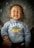 A young child with closed eyes is smiling widely, wearing a gray hoodie with the word 'CHAMPION' and some letters and designs in yellow and red. The child appears to be held by an adult whose hand is visible on the left side of the image, and they are set against a textured background.
