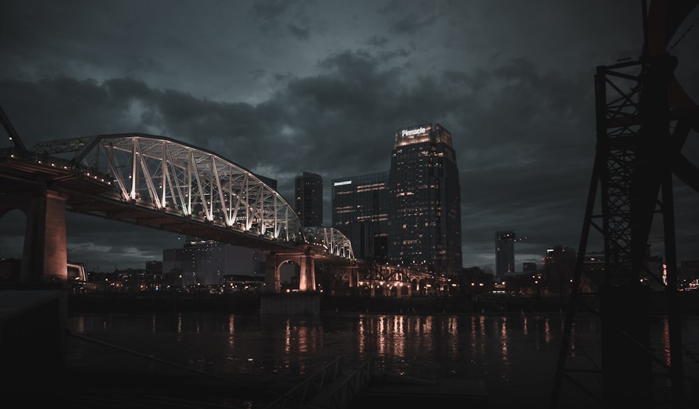 white and black bridge near high rise building at nighttime