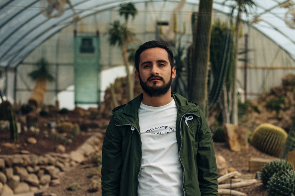 man wearing green zip-up jacket while standing near green trees