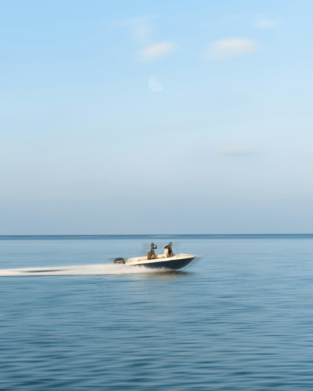 Drei Personen fahren tagsüber auf einem Motorboot unter weißen Wolken