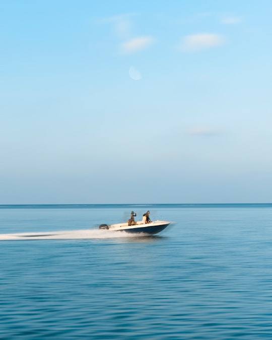 three person riding on motorboat under white clouds at daytime in Hithadhoo Maldives