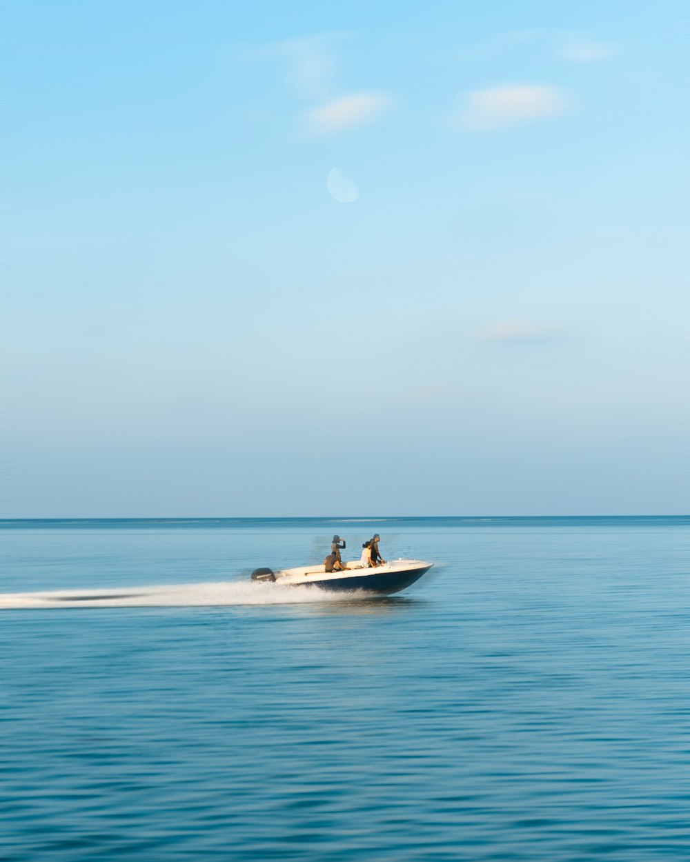 three person riding on motorboat under white clouds at daytime