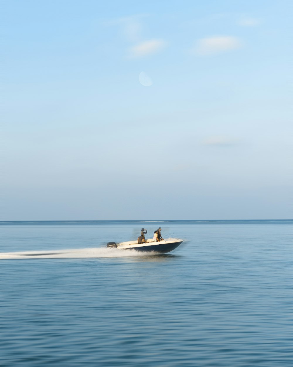 three person riding on motorboat under white clouds at daytime
