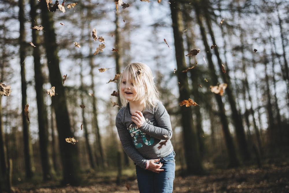 girl in gray long-sleeved top running surrounded with trees