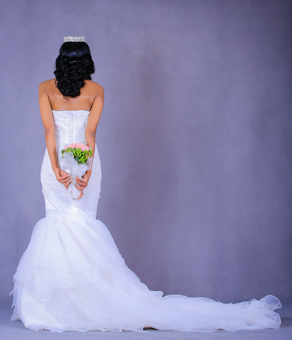 woman holding flower bouquet standing near gray wall