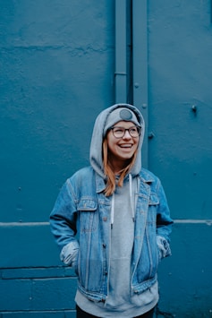 woman in blue jacket standing beside walls