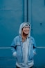 woman in blue jacket standing beside walls
