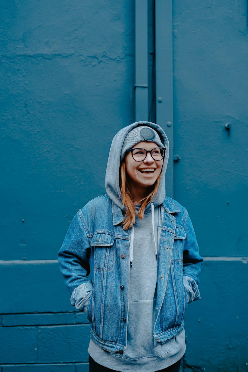 woman in blue jacket standing beside walls