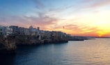 A scenic coastal town with colorful buildings along the waterfront at sunset.