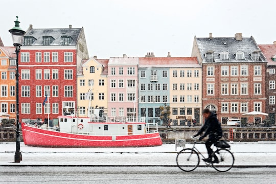 man riding on black bicycle in Nyhavn Denmark