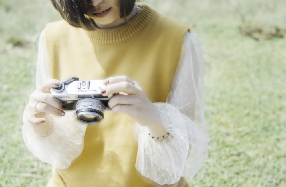 photo of woman holding and looking gray camera