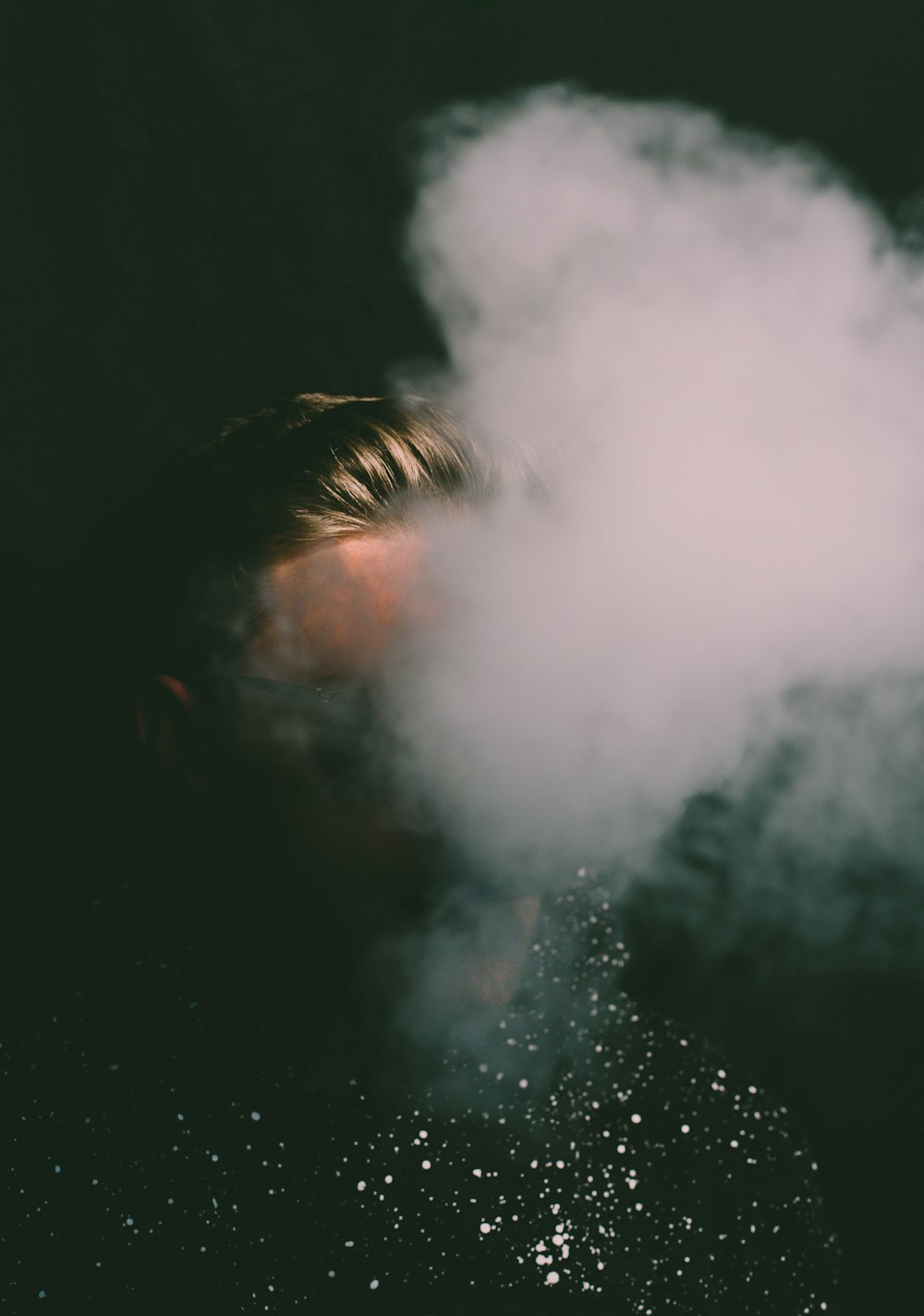 a man with his face obscured by a cloud of smoke
