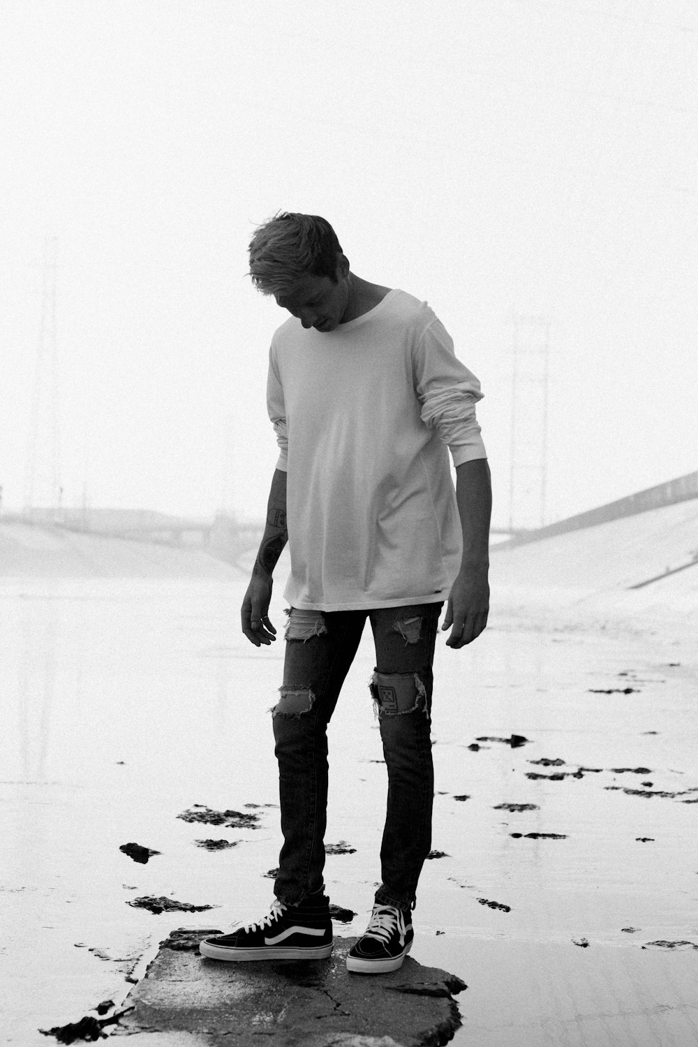man wearing boat-neck long-sleeved shirt and distressed jeans