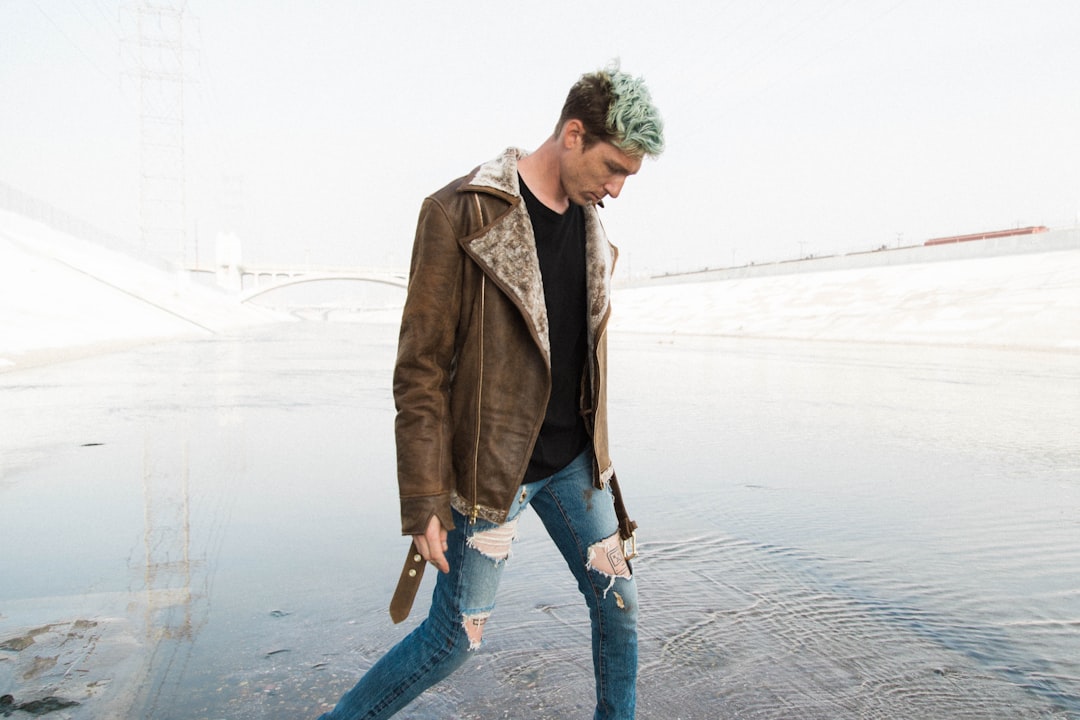 man in brown jacket walking near shore