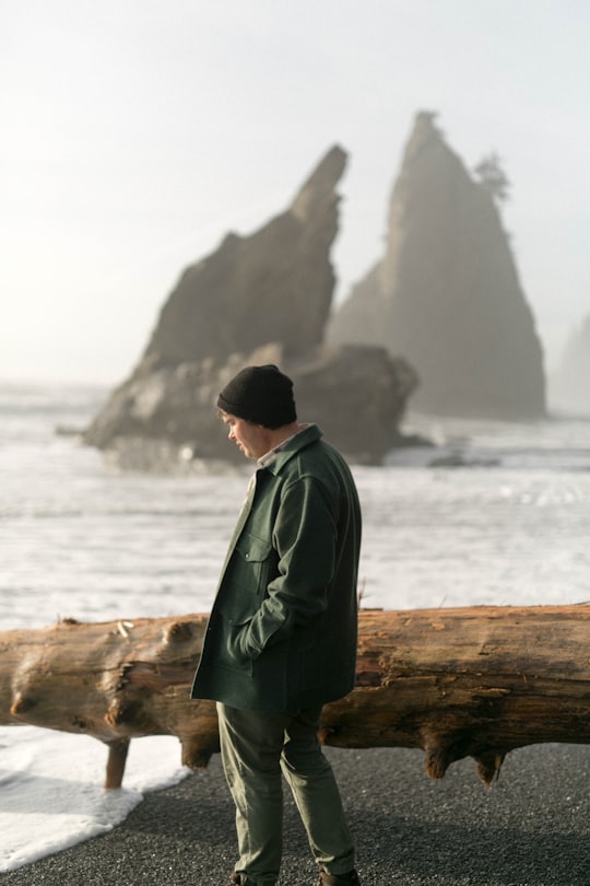 man inserting his left hand inside coat pocket in Rialto Beach United States