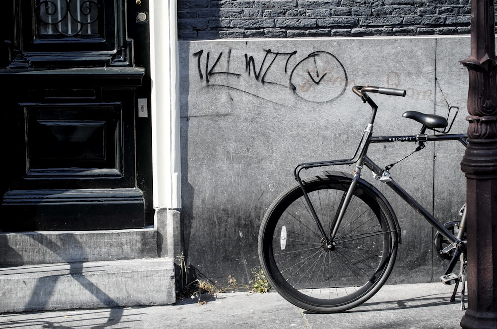 bicycle standing beside gray wall