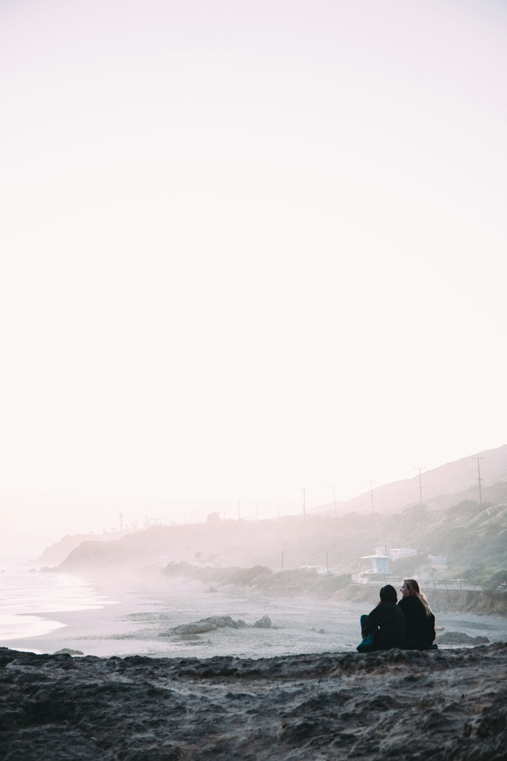 two person sitting beside shore