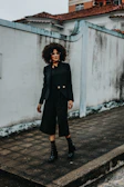 Model wearing a simple black Villegas outfit walking on a white urban street.