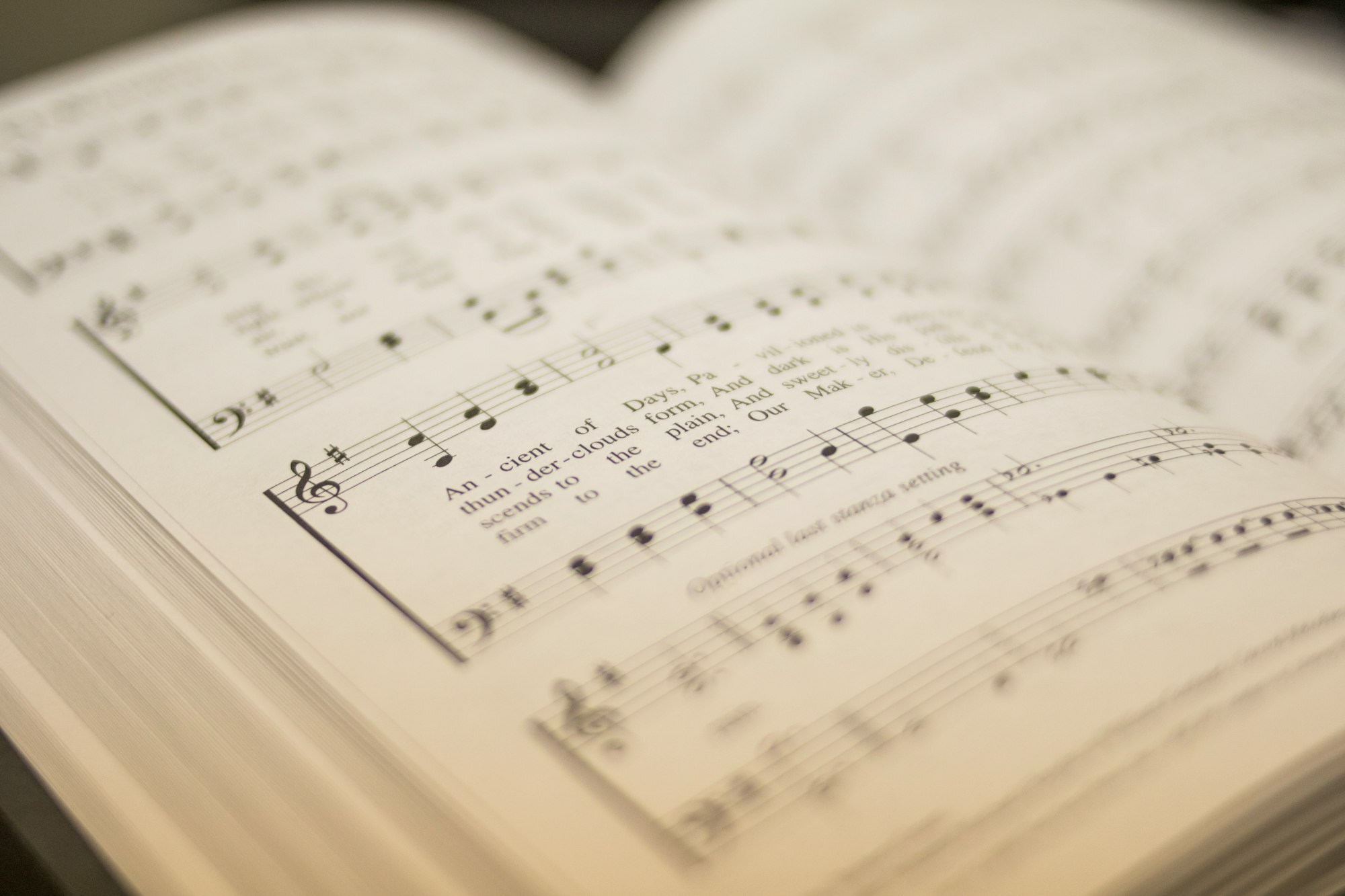 A hymnal open with lyrics and the staff filled with notes.