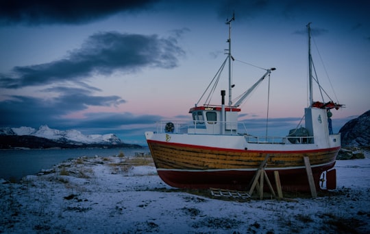 brown and white boat on white sand beach in Sørkjosen Norway