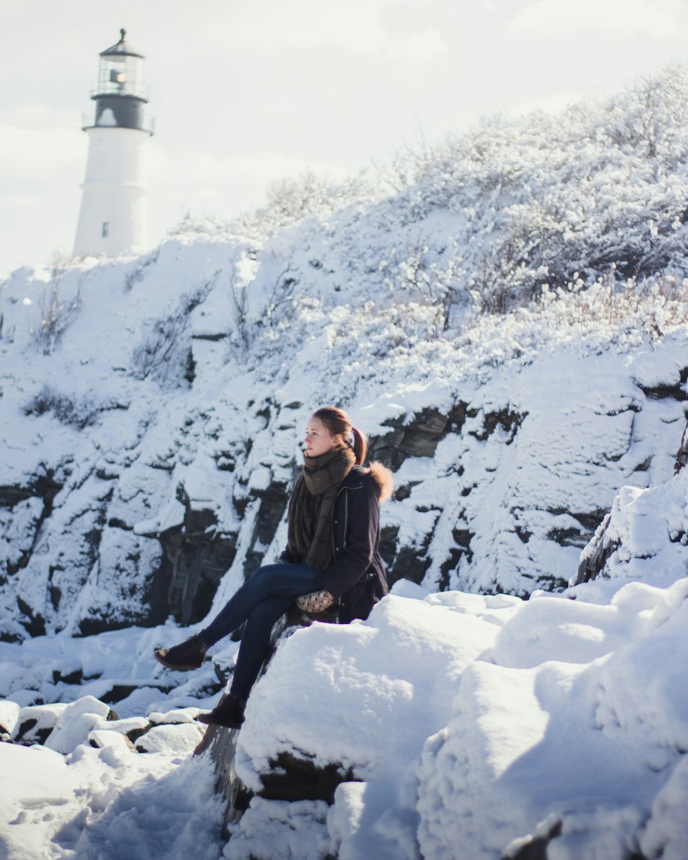 woman in black jacket and black pants sitting on snow covered ground during daytime